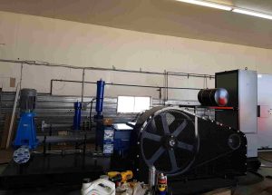 Industrial pump system setup in workshop showing motor-driven equipment and piping, relevant to centrifugal pump vs positive displacement pump comparison.