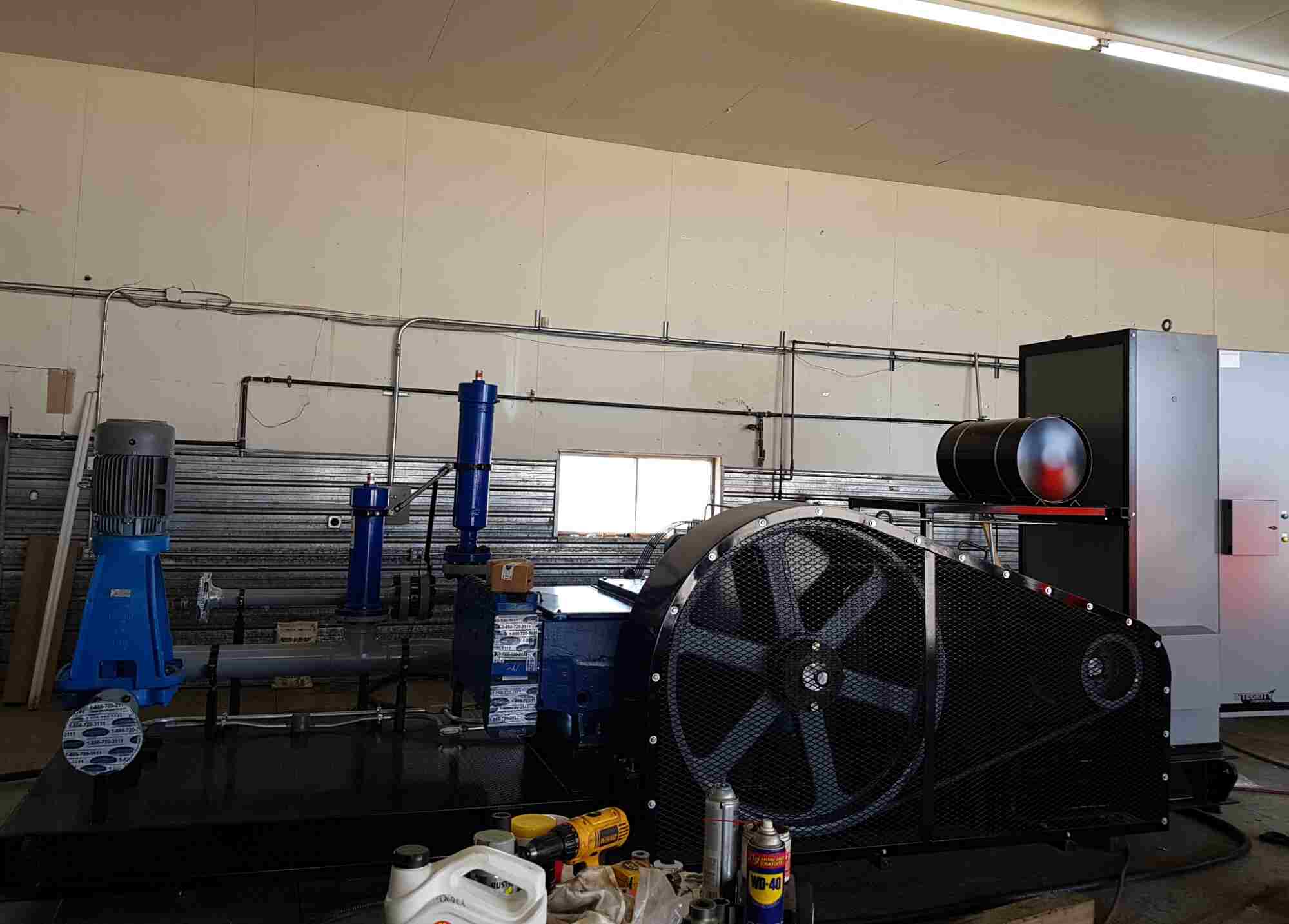 Industrial pump system setup in workshop showing motor-driven equipment and piping, relevant to centrifugal pump vs positive displacement pump comparison.